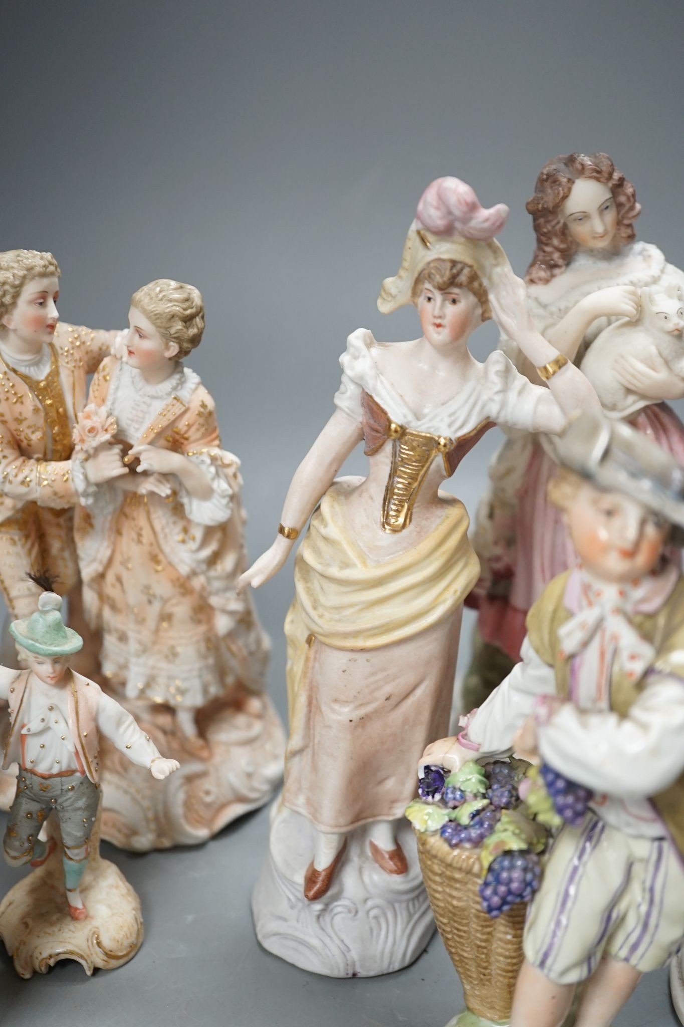 Ten French bisque figures and a Berlin figure of a grape picker, tallest 19cms high.